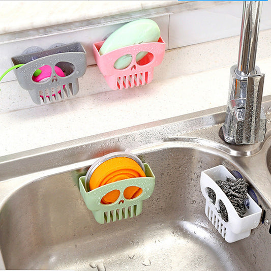 Halloween multi-function dish cloth storage racks in skull design, attached to sink, holding sponges and soap.