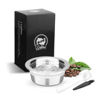 Stainless steel home coffee capsule kit for Lavazza a modo Mio machines, includes two capsules, hammer, grinder, and scoop.