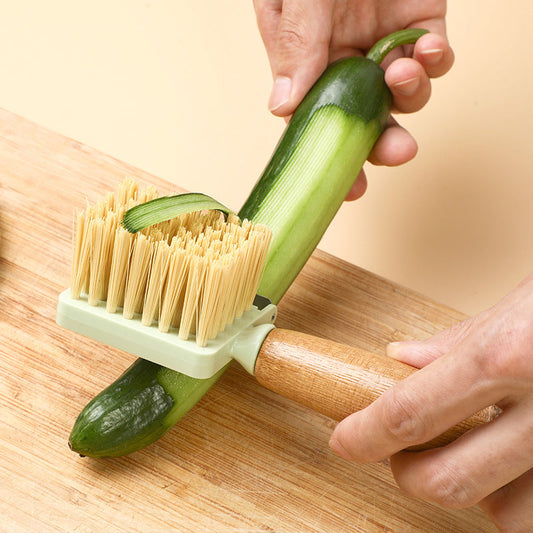 Multifunctional fruit and vegetable brush peeling a cucumber, bamboo handle, green color.